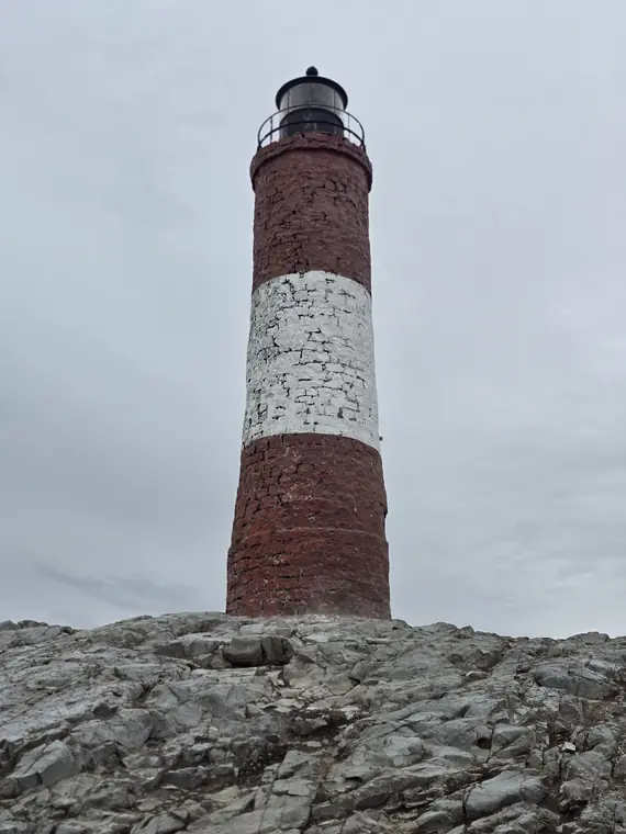 Red and white lighthouse on rocks