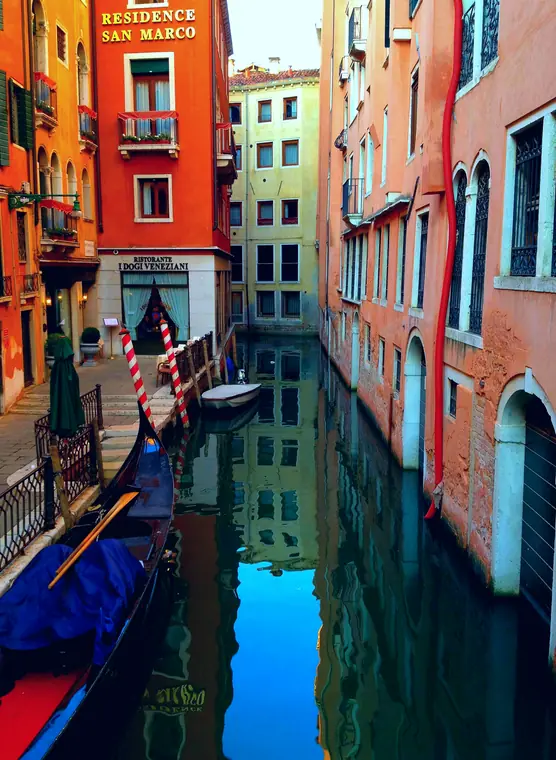 Canal with a gondola between orange buildings
