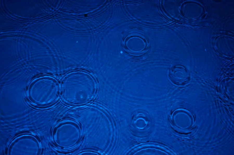 Raindrop rings overlapping on deep blue water